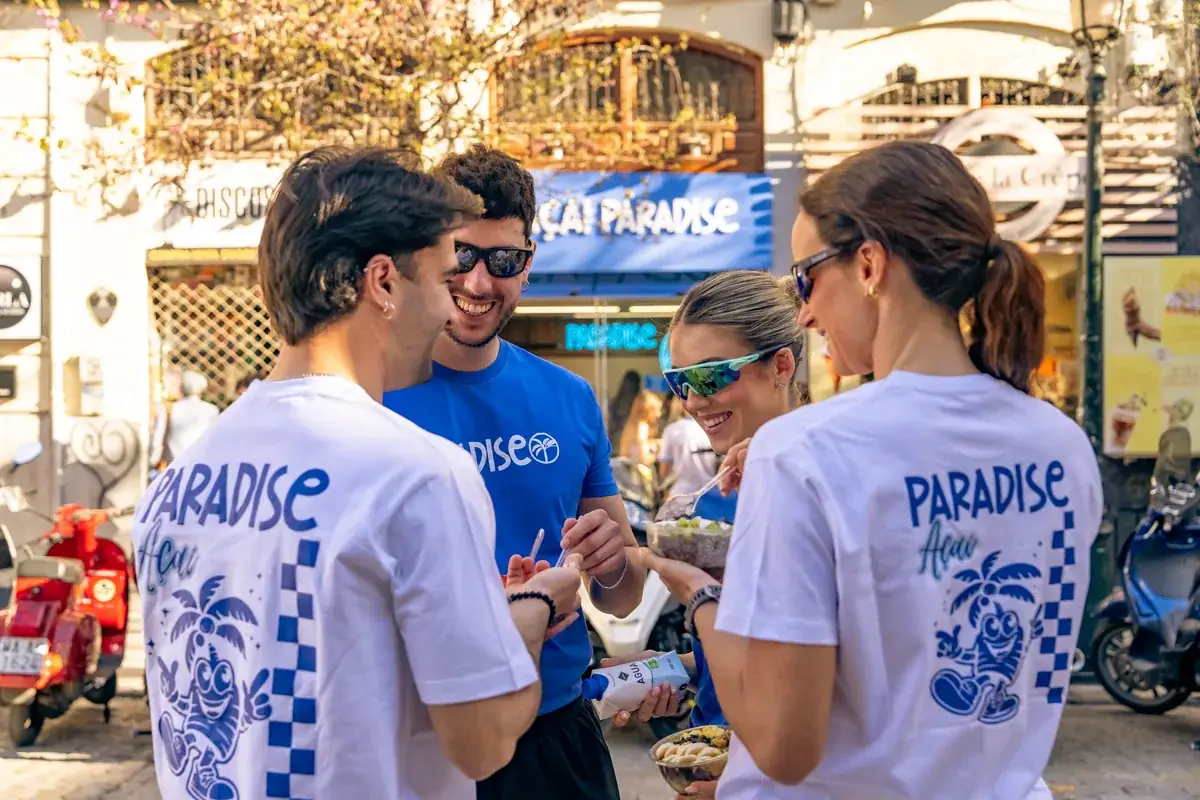 Grupo de amigos riéndose con bowls delante de la tienda Açaí Paradise en Granada