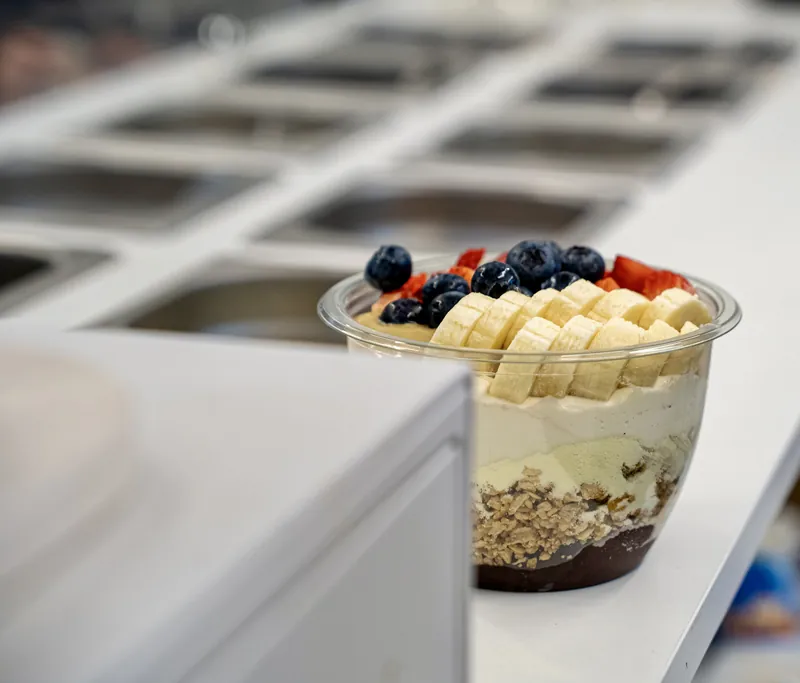 Bowl de açaí preparándose en barra con toppings frescos