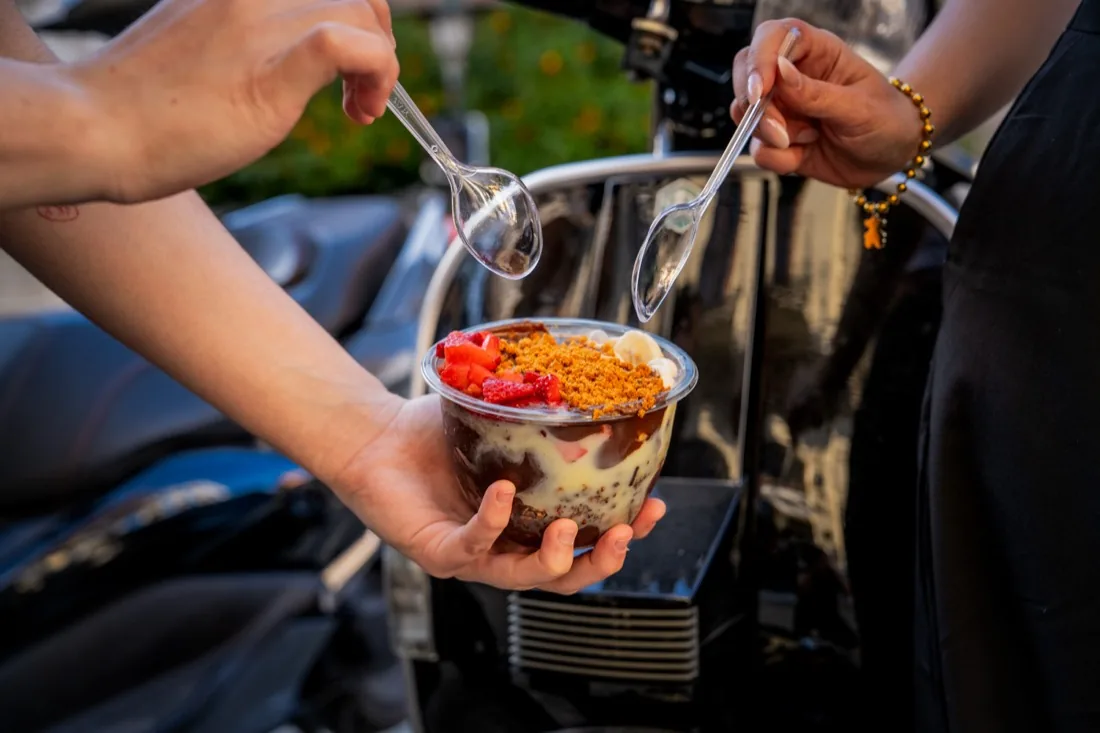 Dos personas compartiendo un acai bowl en la calle al atardecer en Sevilla