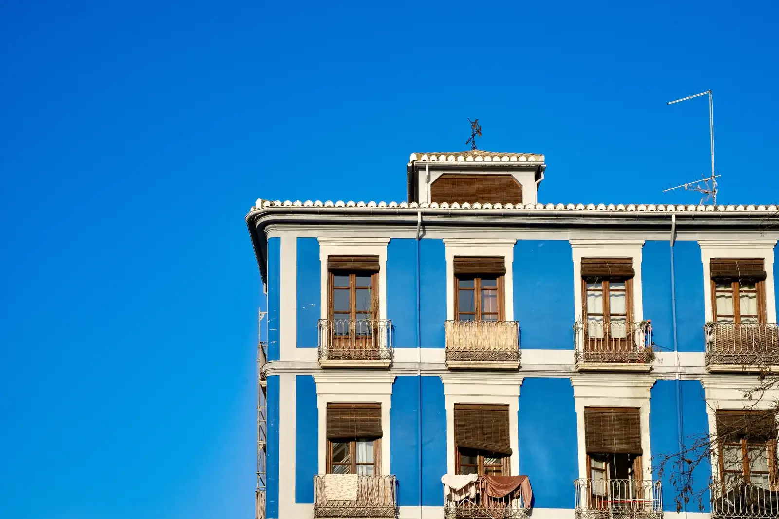 Fachada azul y blanca de un edificio andaluz bajo el cielo despejado