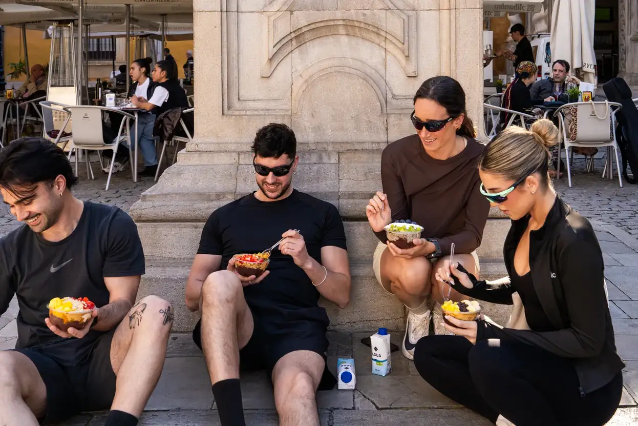 Cuatro amigos comiendo bowls de açaí sentados en una plaza