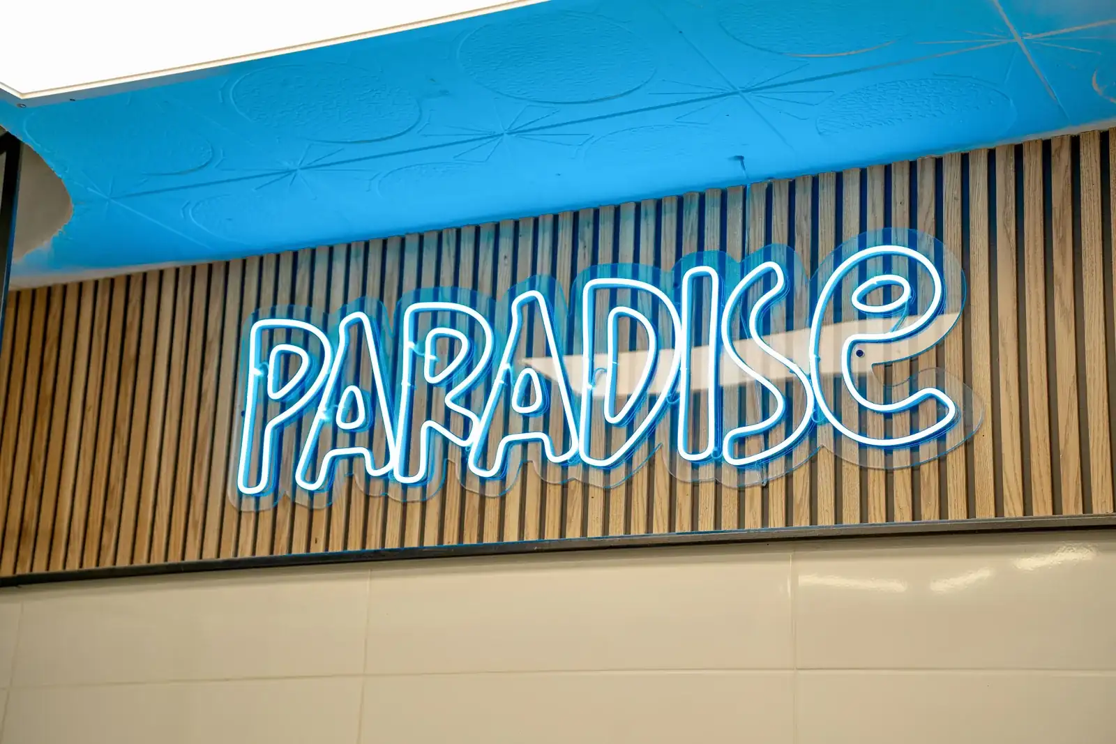Neón Paradise sobre la pared de madera del local